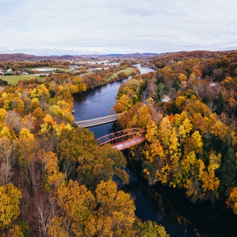 Vista aérea del follaje de otoño y el puente sobre un río (CTVisit)