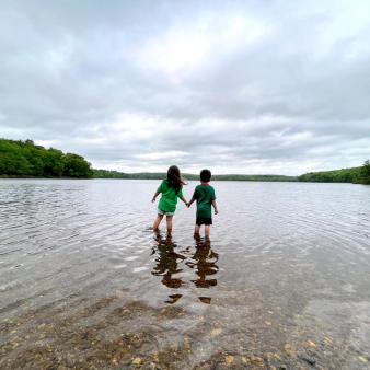 Two kids holding hands wading in the water of the lake (Instagram@loconnecticut)