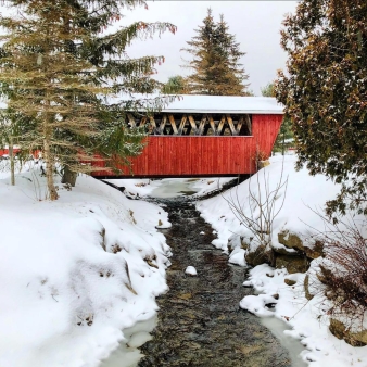 A red covered bridge in the snow (Instagram@newengland-igers)