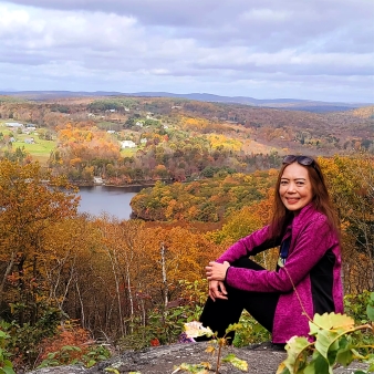 Woman sitting in front of view of fall trees and town (Instagram@dgraygo)