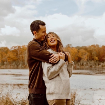 A couple hugging with fall trees in the background (Instagram@hapahana)