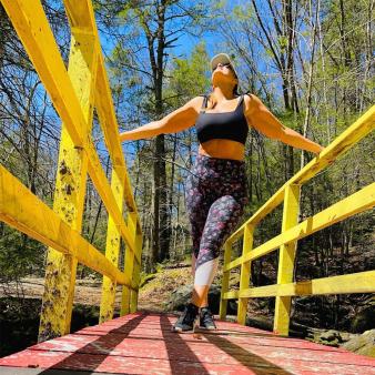 A woman standing on a bridge with yellow rails (Instagram@newnglandergal)