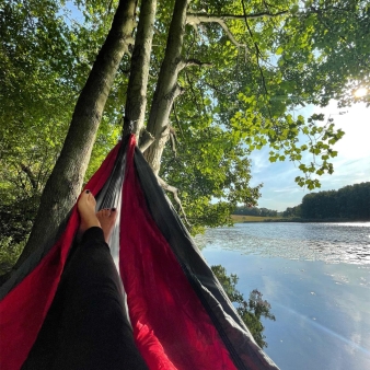 A person sleeping in a hammock near the lake (Instagram@madeyoulookwellness)