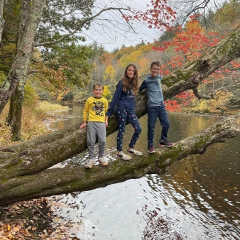 Three kids climbing on a tree over a river (Instagram@anderson.payne1_)