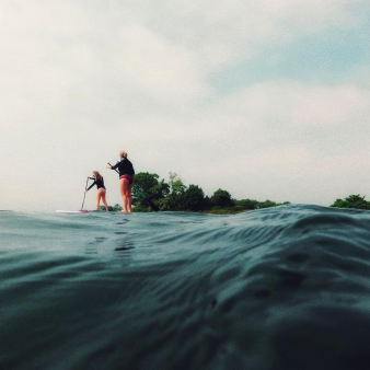 Two women paddleboarding along coastline at Bluff Point State Park (Instagram@krussophoto)