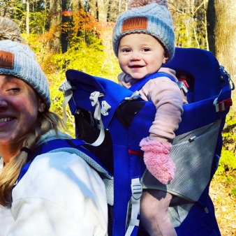 Una madre y su bebé con sombreros a juego, explorando juntos el bosque.
