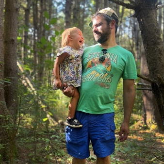 Un hombre sosteniendo a un niño riendo en un hermoso bosque.