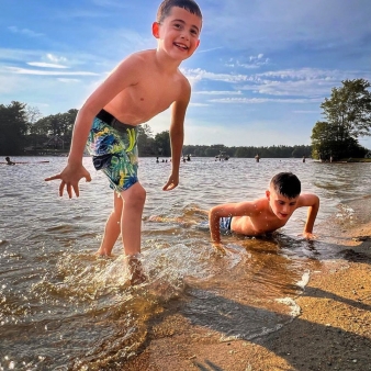 Dos niños chapoteando y divirtiéndose en el agua en un día soleado.