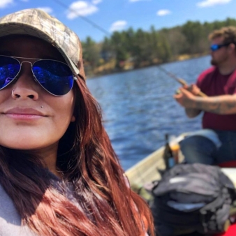 A woman in sunglasses and a hat fishing with her significant other.