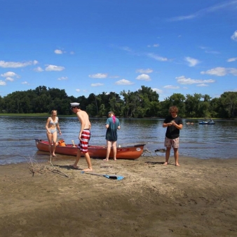 Un grupo de personas en la playa con una canoa, disfrutando del sol y el agua.