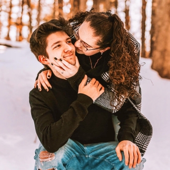 Una pareja posando cariñosamente en el bosque nevado.