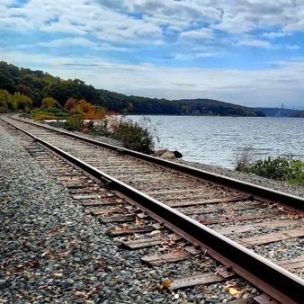 Railroad tracks near water stretching into the distance at Stoddard Hill State Park