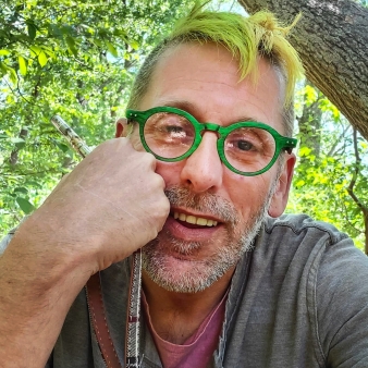 A bearded man wearing green glasses enjoying the outdoors.