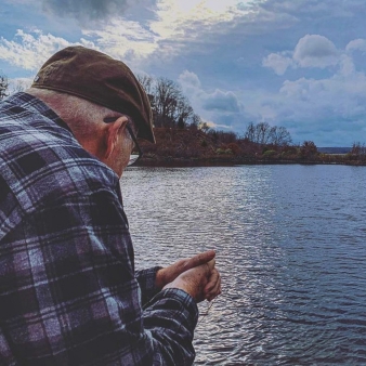 An elderly man enjoying a peaceful day by the water.