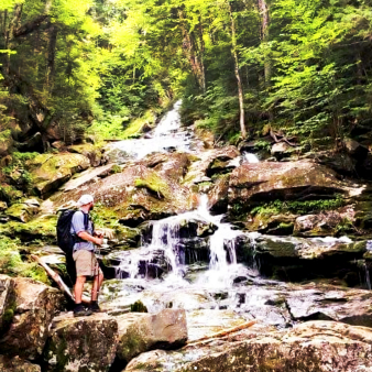 A backpacker enjoying the majestic view of a waterfall.