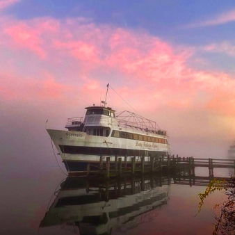 Un barco atracado en aguas brumosas bajo un cielo rosado.