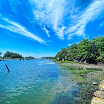 Vista panorámica de aguas tranquilas bajo un cielo azul con nubes esponjosas.