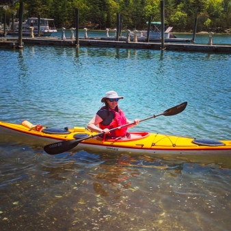 Una mujer en un kayak amarillo flotando en el agua.
