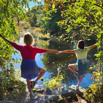 Dos mujeres posaron con gracia sobre una roca con vistas al agua.