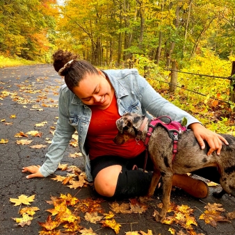 Una mujer se arrodilla amorosamente en el suelo junto a su perro rodeada por la vibración del otoño.