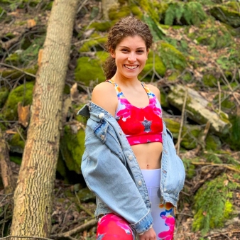 Una mujer joven posó en el bosque vistiendo un conjunto de ropa colorida y una chaqueta de mezclilla.