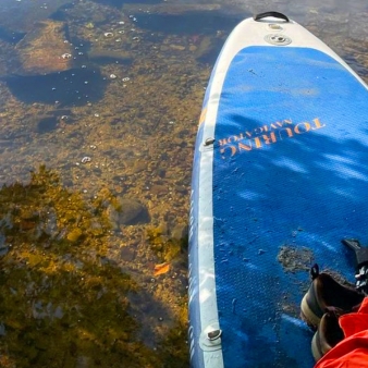 A person on a paddle board in shallow water.