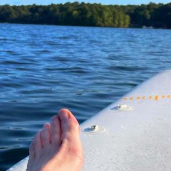 A person's feet on a paddle board gliding through the water.