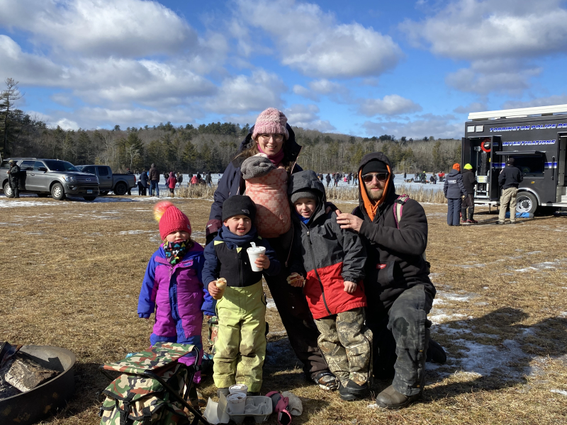 Family at winter festival standing in front of frozen pond