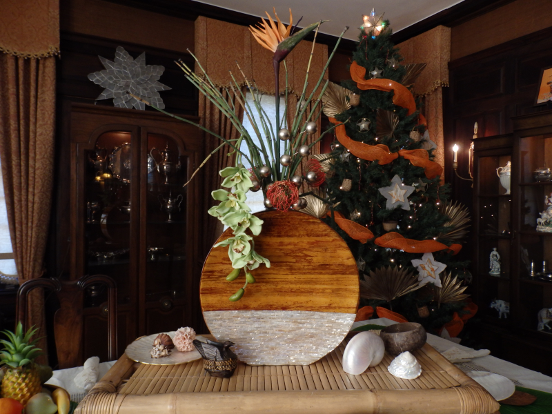 Photo of round vase with orchids with decorated holiday tree in the background representing the Philippines. 