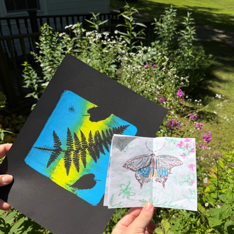Estampado de un helecho y dibujo de una mariposa negra frente a flores de jardín.