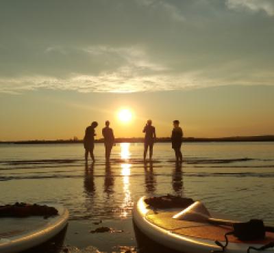 Grupo en la costa de CT durante la puesta de sol con kayaks en primer plano