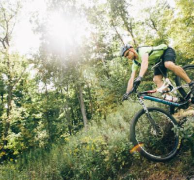 Hombre ciclismo de montaña a través de bosques