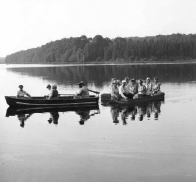 Historical black and white photo of people in two boats on a lake