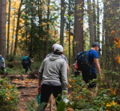 Una vista detrás de personas caminando y explorando un sendero boscoso.