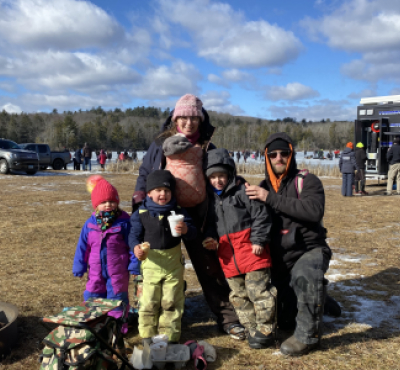 Familia en un festival de invierno de pie frente a un estanque congelado