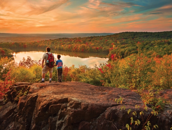 Padre e hijo viendo la puesta de sol en Crescent Lake en Mattabesset Trail