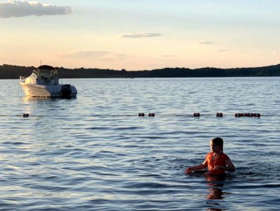 niña nadando en el lago con un barco al fondo (Instagram@sarateidee)
