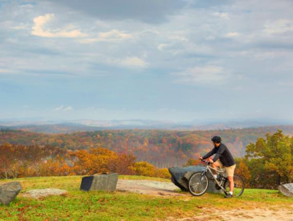 Un hombre en bicicleta en la cima de la montaña contempla la vista (CTVisit)