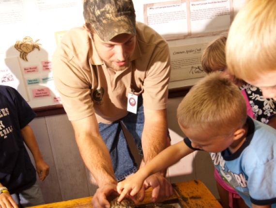 Man walking kids through nature center observation display