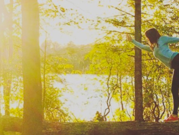 Woman yoga posing on downed tree