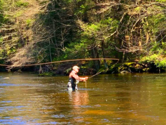  Un hombre pescando en un río con una caña de pescar.