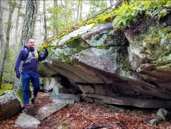 Man hiking along rock formation at Nehantic State Forest